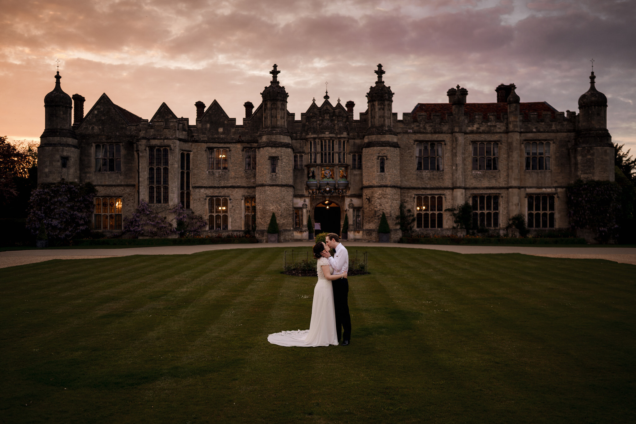 Bride and Groom infron of Hengrave Hall at sunset with a beautiful sky.